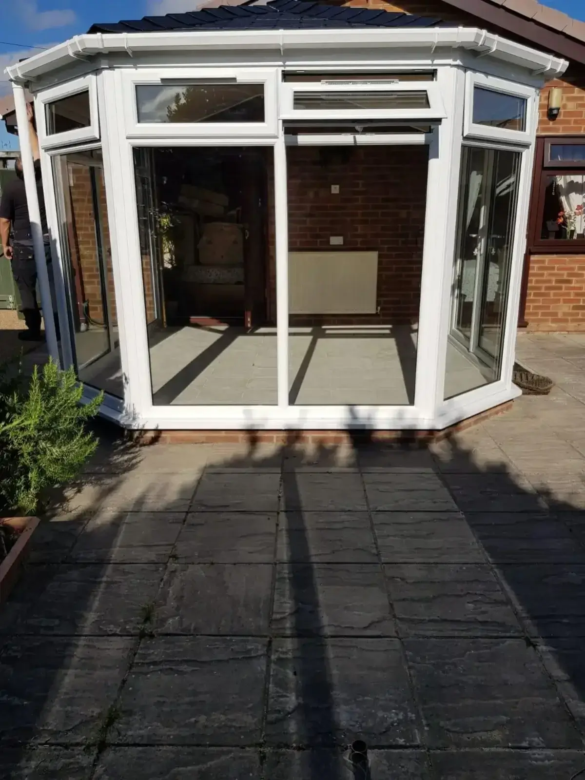 Finished white uPVC Victorian conservatory featuring a high-performance tiled roof system and modern patio flags. By Norfolk Exterior Solutions